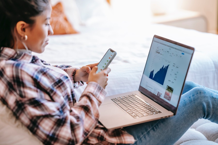 Ragazza con smartphone in mano e computer sulle gambe