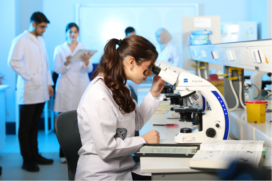 Giovane scienziata che esamina campioni al microscopio in un moderno laboratorio