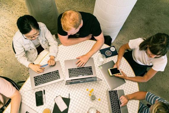 persone sedute a un tavolo che usano computer e telefono