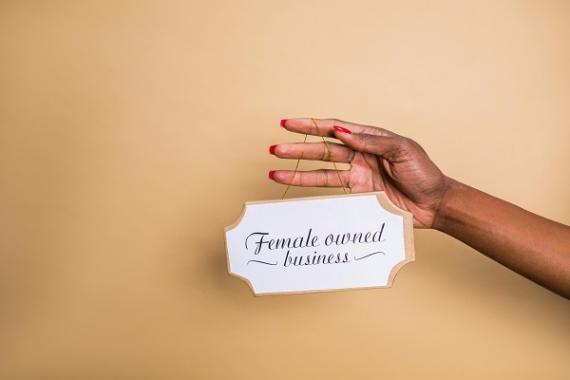 una donna regge un cartello con scritto "female owned business"