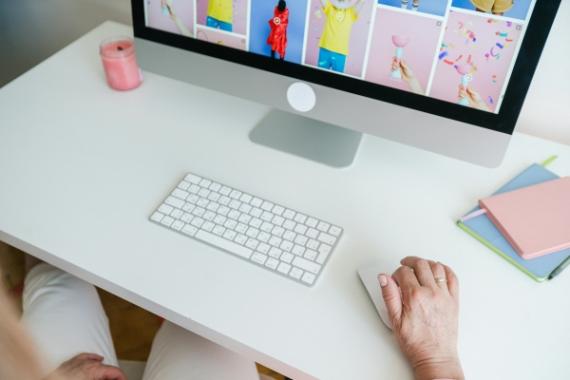 Scrivania bianca con tastiera bianca, computer, agenza e contenuti colorati sullo schermo