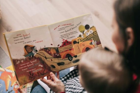 Ragazza che accudisce un bambino e legge un libro colorato