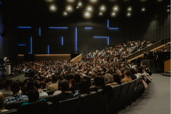 Un ampio pubblico ascolta attentamente un relatore a una conferenza